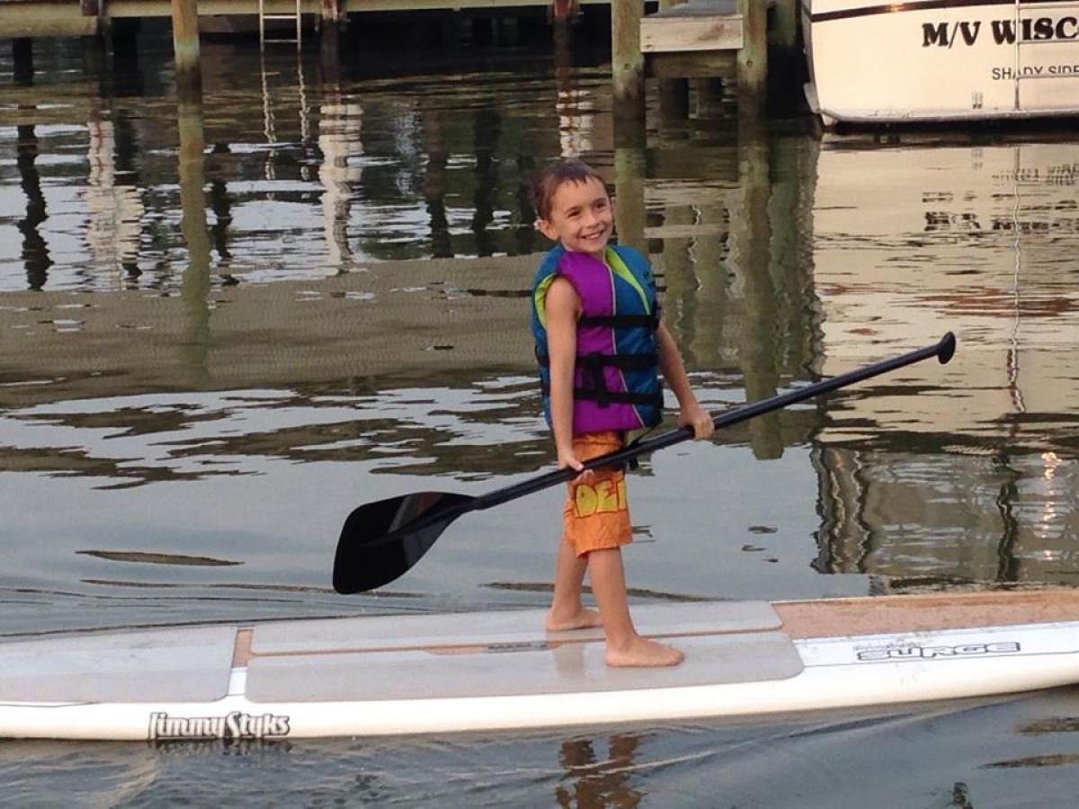 A happy kid paddles around in the bay