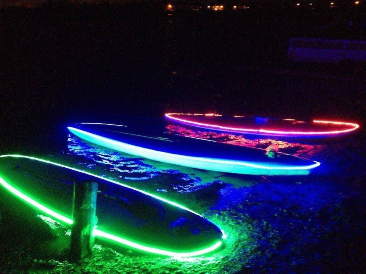A shot of the glowing SUP boards on the water at night