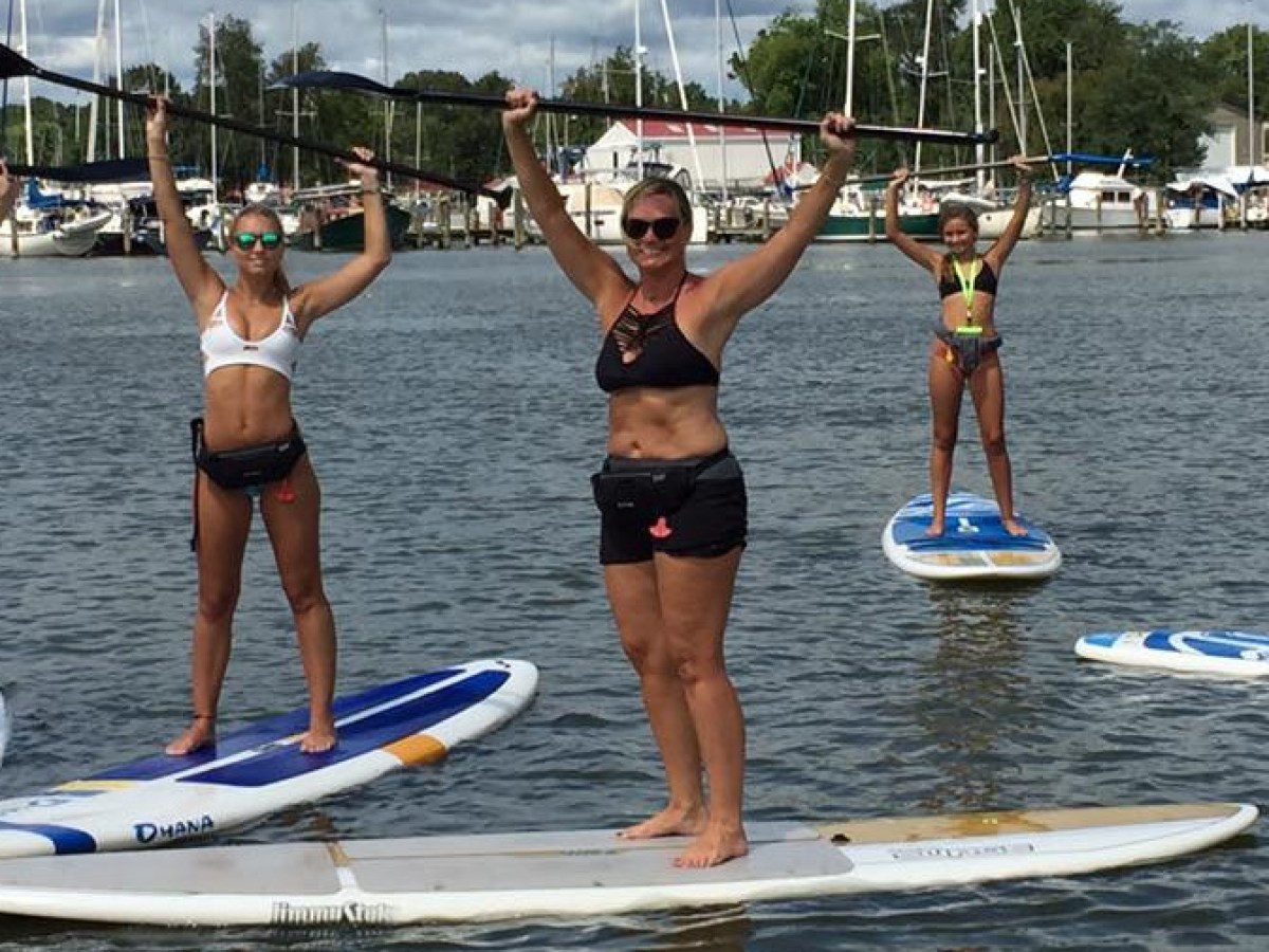 Small group of people on their SUPs holding paddles above their heads
