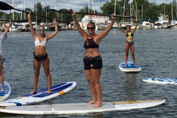 Small group of people on their SUPs holding paddles above their heads