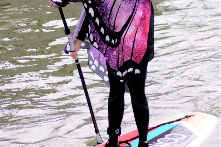 a little girl standing next to a body of water