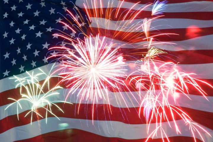 Fireworks exploding in front of an American flag backdrop.